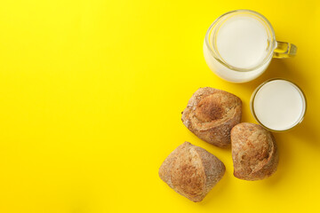 Fresh baked buns and milk on yellow background