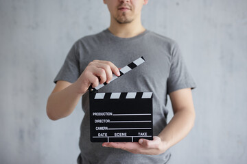 videography and filmmaking concept - young man holding clapper board in his hands