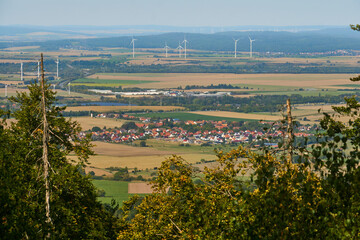 View over the trees to a village in the Vorharz Wind turbines in the flat country, Bad Harzburg, Germany