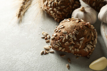 Fresh baked garlic buns and wheat ears on light gray table