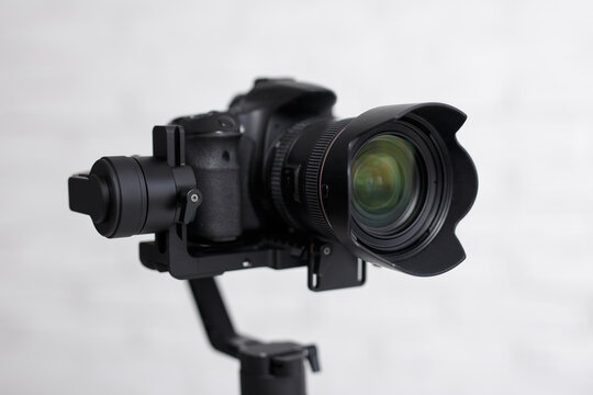 photography or videography kit - close up of modern dslr camera on 3-axis gimbal stabilizer over gray