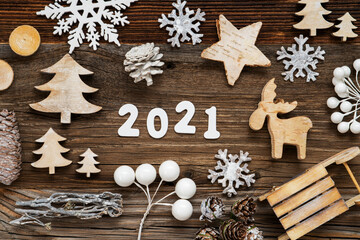 White Letters Building The Word 2021. Wooden Christmas Decoration Like Tree, Sled And Star. Brown Wooden Background