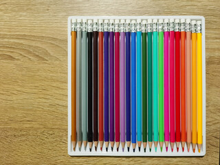 A set of colored pencils on a wooden table surface