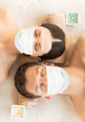 Obraz na płótnie Canvas wellness, bodycare and health concept - couple wearing face protective medical mask for protection from virus disease at aromatherapy at spa session