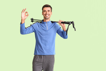 Young man with walking poles showing OK on color background