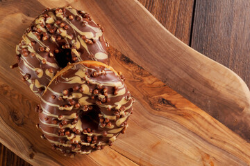 Fresh tasty chocolate with sugar icing donuts on a wooden board. Black background. Bakery product