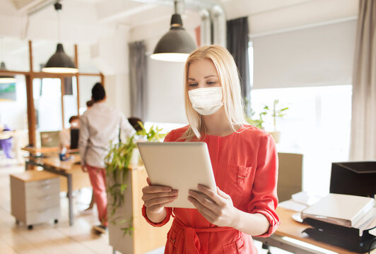 business, health and people concept - businesswoman or creative female office worker wearing face protective medical mask for protection from virus disease with tablet pc computer