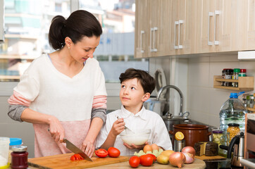 Smiling teen boy with his mother preparing family dinner together at home kitchen