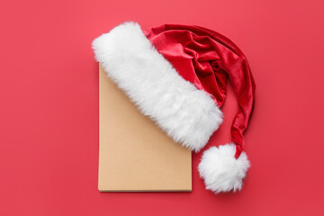 Santa hat and blank card on color background