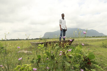 young Indian man standing on a boat, mountain in background