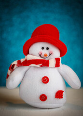 Smiling snowman toy dressed in scarf and cap.