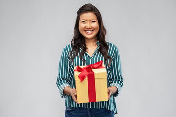 Fototapeta premium birthday present and surprise concept - happy asian young woman with gift box over grey background