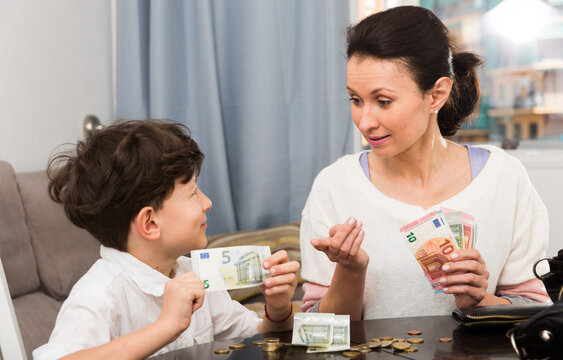 Children and money concept. Woman admonishing teen boy while giving him money at home