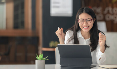 Young successful businesswoman raising her hands up and laughing with happiness.