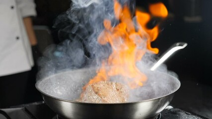Cooking and serving food in restaurant. Chef making steak fillet mignon in flambe style on grill pan. Cooking slow motion. Cooking Beef meat Stroganoff with Open Flames. Full hd