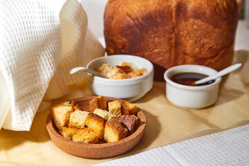 Square toasted pieces of homemade delicious rusk, hardtack, Dryasdust, zwieback, bread, Liquid honey and plate with milk in a white plate on a white tablecloth.