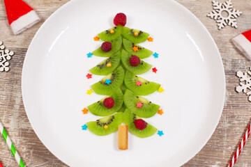 Christmas tree made of kiwi slices on wooden table.