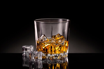 Crystal glass of whiskey with ice cubes on black background.