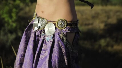 Girl in oriental dress dancing belly dance in nature on a sunny day