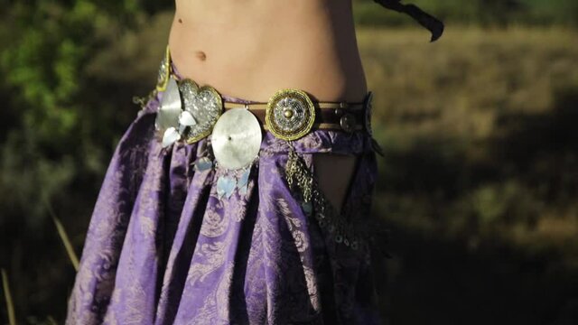 Girl in oriental dress dancing belly dance in nature on a sunny day