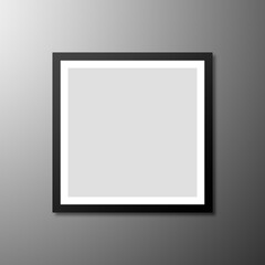 Blank square photo frame on a gray wall with a gradient of incident light.