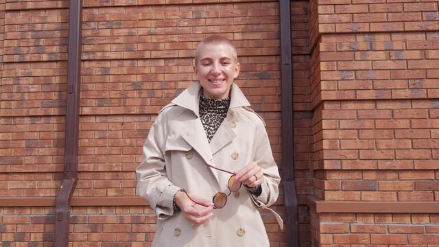 A woman with short hair in a leopard turtleneck and coat smiling at camera on a city street.