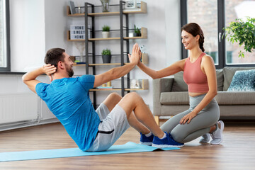 Fototapeta premium fitness, sport, training and healthy lifestyle concept - man with personal trainer doing sit ups at home