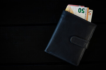 Abstract and conceptual black wallet, on black wooden table. with money paper currency euro banknote