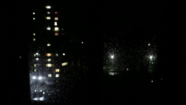 Raindrops on the window, view from the window of the house to the street, background. Lantern and car lights, copy space for text, nighttime