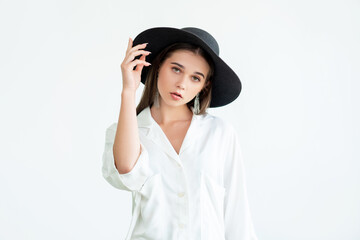 Trend fashion look. Casual style shooting. Elegant young woman in wide-brimmed black hat vintage earrings white shirt isolated on neutral. Boho lifestyle. Advertising background