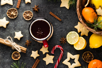 hot tea in a red mug in a new year's atmosphere. Christmas morning. A mug with a drink next to Christmas tree branches, oranges, spices and cookies