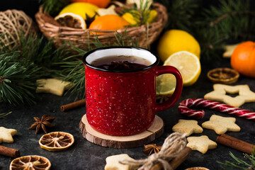 hot tea in a red mug in a new year's atmosphere. Christmas morning. A mug with a drink next to Christmas tree branches, oranges, spices and cookies