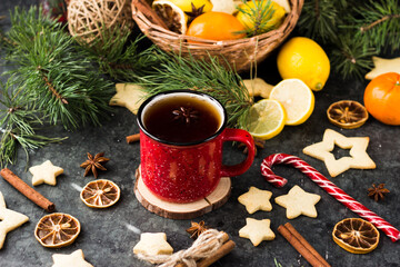 hot tea in a red mug in a new year's atmosphere. Christmas morning. A mug with a drink next to Christmas tree branches, oranges, spices and cookies