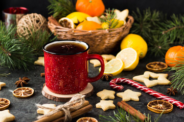 hot tea in a red mug in a new year's atmosphere. Christmas morning. A mug with a drink next to Christmas tree branches, oranges, spices and cookies