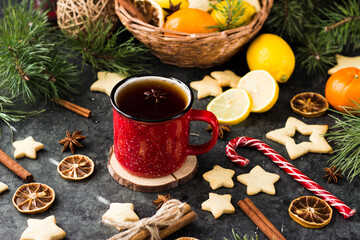 hot tea in a red mug in a new year's atmosphere. Christmas morning. A mug with a drink next to Christmas tree branches, oranges, spices and cookies