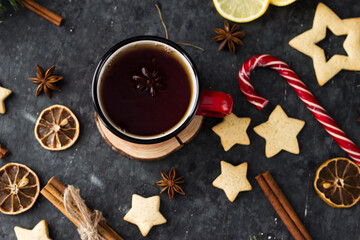 hot tea in a red mug in a new year's atmosphere. Christmas morning. A mug with a drink next to Christmas tree branches, oranges, spices and cookies