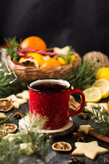 hot tea in a red mug in a new year's atmosphere. Christmas morning. A mug with a drink next to Christmas tree branches, oranges, spices and cookies