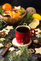 hot tea in a red mug in a new year's atmosphere. Christmas morning. A mug with a drink next to Christmas tree branches, oranges, spices and cookies