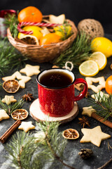 hot tea in a red mug in a new year's atmosphere. Christmas morning. A mug with a drink next to Christmas tree branches, oranges, spices and cookies