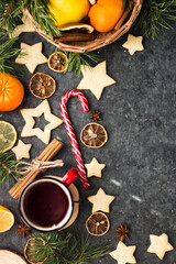 Fototapeta na wymiar hot tea in a red mug in a new year's atmosphere. Christmas morning. A mug with a drink next to Christmas tree branches, oranges, spices and cookies