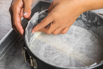 A cake tin line with wax paper and wrap in aluminum foil on a tray for putting a water bath before...