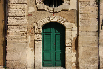 Portale d’ingresso di colore verde, in un antico palazzo in pietra, in città
