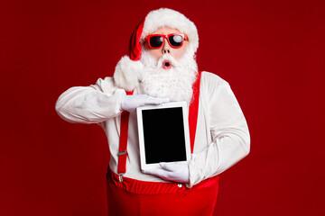 Portrait of his he attractive amazed stunned fat white-haired Santa holding in hands ebook gadget...