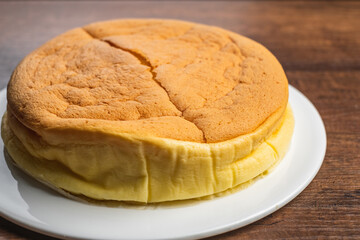 Freshly baked japanese fluffy soft cheesecake on white plate on wood table top background.