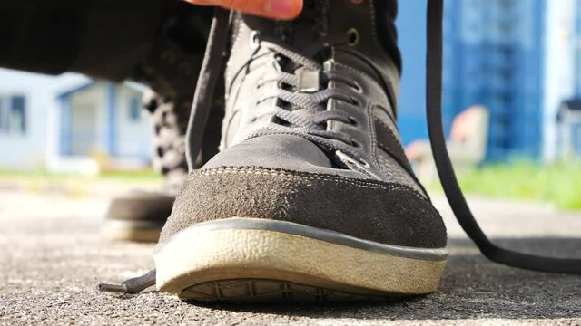 A man laces his sport shoe outdoors close up
