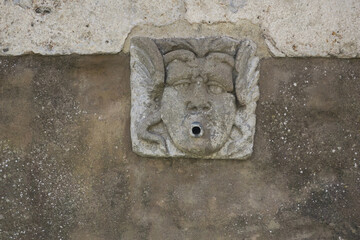 gargoyle on a wall of a fountain in Pitigliano Italy