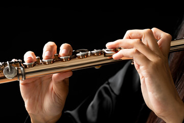 Close up of the hands of a young woman playing a golden flute
