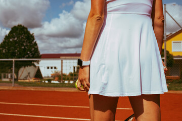 a tennis player in a white dress stands on the court and holds a tennis ball in her hand