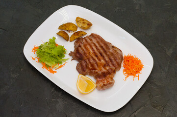 Grilled beef or veal meat steak with lemon, carrots, lettuce and potatoes. Juicy and very tasty dish of Italian cuisine
