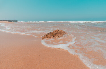 A wave flows around a rock, on a beach in the sea of Ashdod, Israel